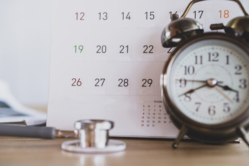 doctor office with calendar , alarm clock and stethoscope on desk 