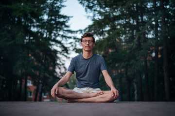 6392804 Man practicing meditation in city.