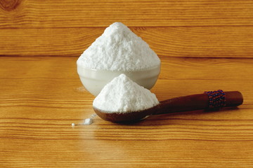 baking soda or baking powder in spoon and bowl isolated in wooden background for cooking recipe or cleaning