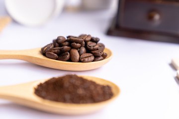 wooden spoons filled with crushed ground coffee on white background, close up