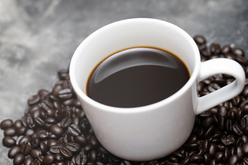 White coffee cup and coffee beans dark on table Bare mortar cement style loft background. soft focus.	