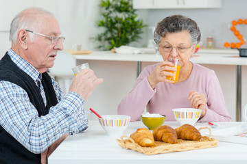 aged couple having fun in the kitchen at breakfast time
