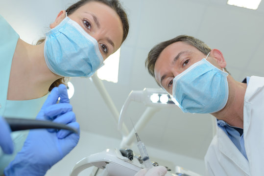 female dentist and assistant examining patients mouth