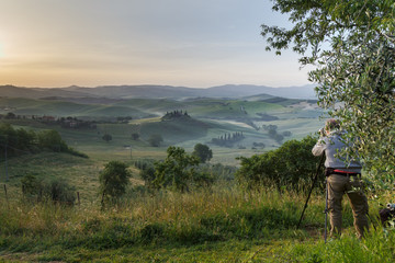 Fototapeta na wymiar Photographing at sunrise beautiful Tuscany landscape with traditional farm house, hills and meadow. Val d'orcia, Italy. Holidays in Italy.