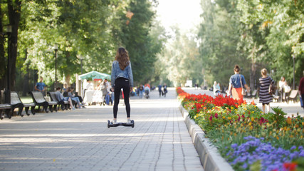 Slender beautiful girl riding a gyro in the park, moving from the camera