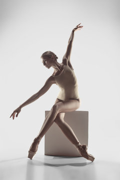 Young graceful female ballet dancer or classic ballerina dancing on white studio. Caucasian model on pointe shoes