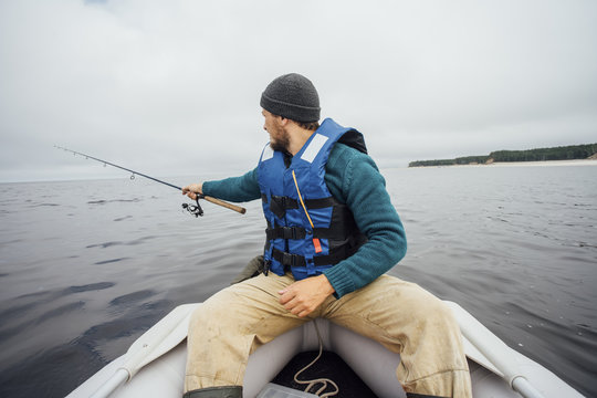 Man sitting on boat fishing with fishing rod