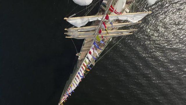Aerial Top Beautiful Big old wooden fregat Sailing vessel Ship Wind flags. Open ocean sea dark shiny water. People sailors on board. Competition regatta Cruise. Travel. Russia Europe Asia. Helicopter 