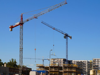 Three cranes at work. View of the house construction site.