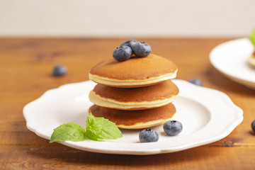 Delicious close-up pancakes with fresh blueberries and mint on a white plate
