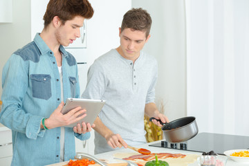 2 young men cooking together at home
