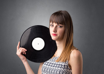 Young lady holding vinyl record on a grey background
