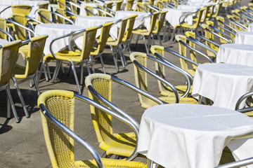 Rows of tables and chairs on the street in a restaurant 