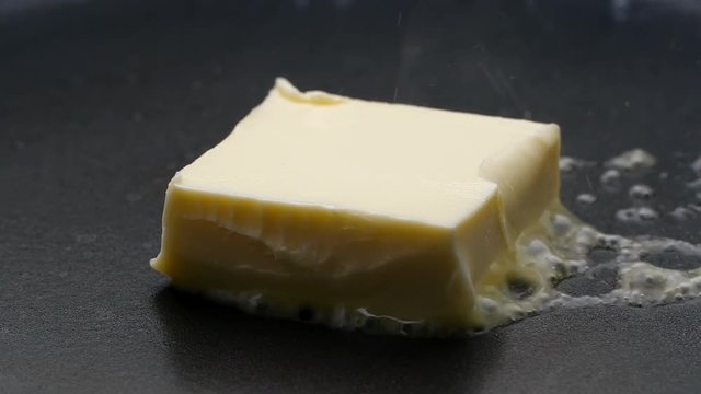 Butter melting sizzling in frying pan on stove. Close up.

