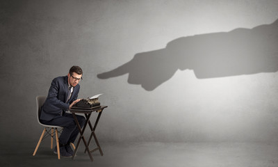 Shadow hand pointing at a small afraid worker
