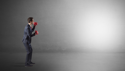 Businessman fighting with boxing gloves in an empty space
