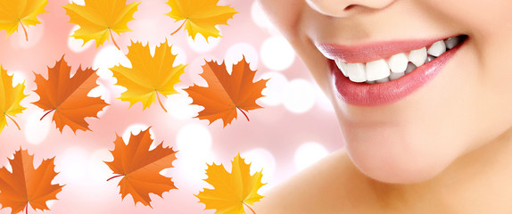 Closeup shot of female smile and maple leaves on background