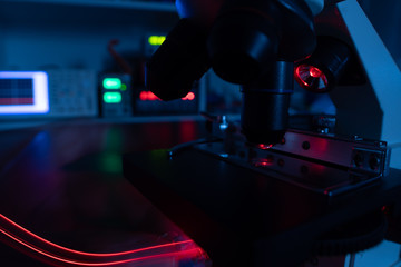 Closeup lens of a modern microscope in a research lab on a dark