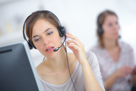 woman working on computer with headset in office