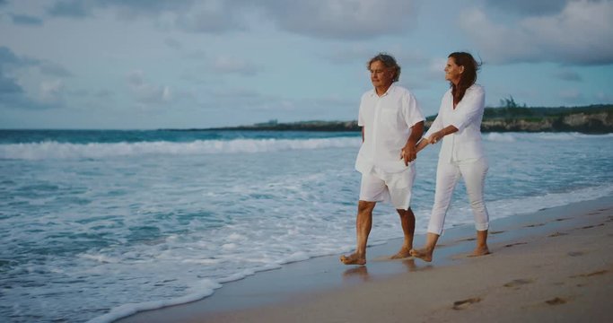 Middle age couple enjoying sunset walk on the beach