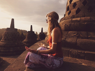Young woman practicing yoga - meditation on the biggest Buddhist temple - Borobudur.