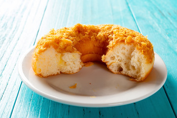 side view studio shoot of donut with shredded pork on top with some bites