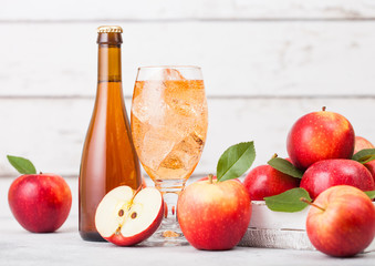 Bottle and glass of homemade organic apple cider with fresh apples in box on wooden background