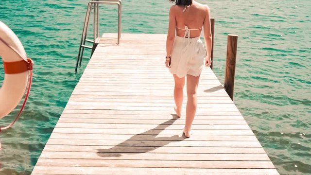 Young woman walking on a dock in Worthersee lake, Austria mountain view windy hair in slow-motion