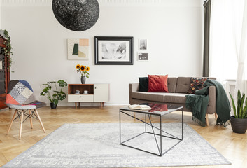 Industrial black coffee table with marble surface and a colorful patchwork chair in a living room...