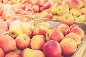 red ripe apples in wooden boxes for sale at street market, retro toned