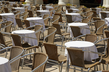 Sidewalk tables and chairs in a sunny summer day in Italy, nobody