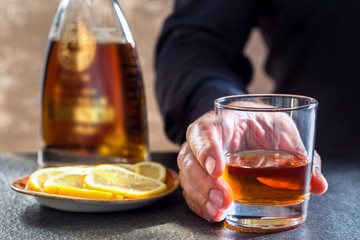 Men hand with drink and whiskey bottle on table of bar.