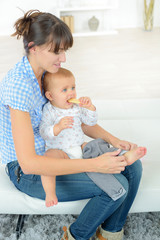 mother dressing her baby on a couch