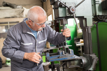 elderly worker watches processing of detail on milling machine - obrazy, fototapety, plakaty