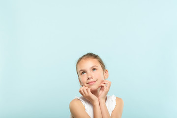 smiling cute pensive young girl looking up at a virtual object or text speech bubble. empty space...