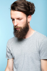 sad depressed frustrated dull bearded man. portrait of a disappointed sullen hipster guy on blue background. people emotions and facial expressions concept.