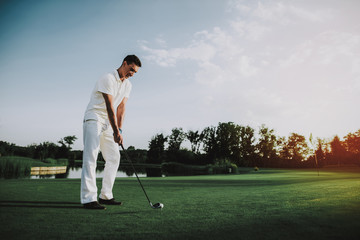 Fototapeta premium Young Man in White Clothes Playing Golf on Field.