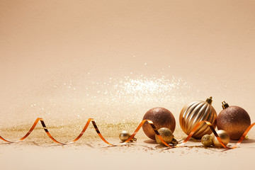 sparkling bright christmas balls and wavy ribbon on beige tabletop
