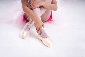 The lady hand is touching satin ballet shoe with right hand,