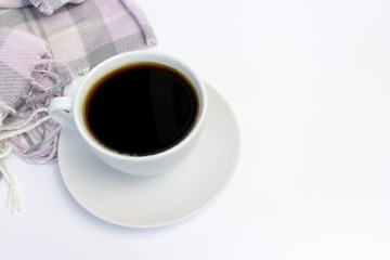 White ceramic cup of coffee and pink knitted plaid on white with copy space