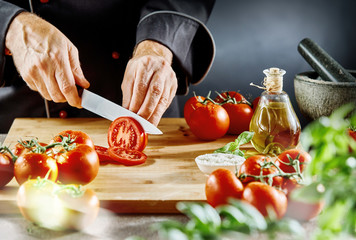 Man cutting ripe tomatoes into thin slices