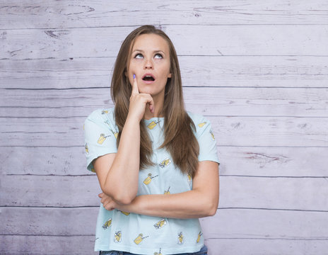 white girl with long hair holds the hand with the index finger near the face with a thoughtful expression, smotreti up, thoughtful women, emotions