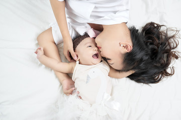 Fototapeta na wymiar Mother kisses baby lying on the bed closeup