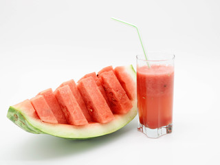 Watermelon slices and a glass of watermelon juice with a straw.