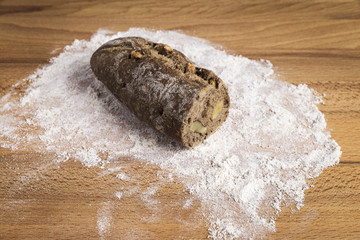 small bar of wholemeal bread with freshly made walnuts next to some ingredients on a wooden table
