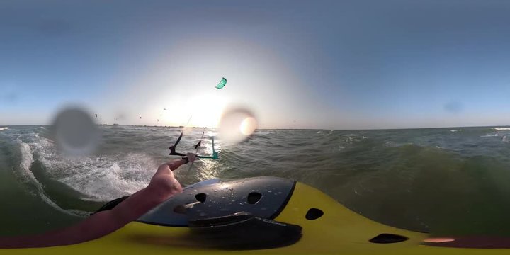 Athletic man in helmet with camera 360 engaged in kyurfing in the sea during the dawn