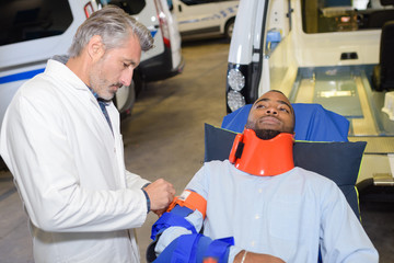 Man on ambulance stretcher wearing neck and arm brace