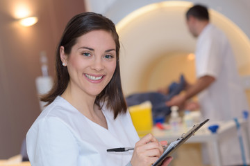 doctor reading clipboard with colleague preparing patient for ct