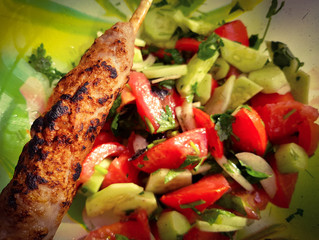 barbecue on wooden stick on tomato and cucumber salad background 