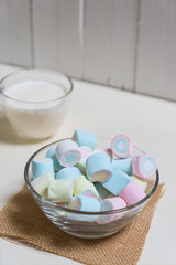 Marshmallows in glass cup on hot milk with white cup,